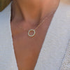 Woman with a Rosecliff open circle necklace with 16 alternating 2 mm round cut peridots & diamonds prong set in 14k gold