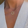 Woman wearing a Rosecliff open circle necklace with sixteen 2 mm faceted round cut peridots prong set in 14k gold