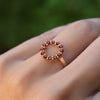 Hand wearing a Rosecliff small open circle ring featuring twelve 2 mm faceted round cut garnets prong set in 14k yellow gold