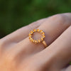 Hand wearing a Rosecliff small open circle ring featuring twelve 2 mm round cut citrines prong set in 14k yellow gold