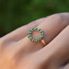 Hand with a Rosecliff small open circle ring featuring twelve 2 mm round cut emeralds prong set in 14k yellow gold