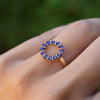 Woman's hand wearing a Rosecliff small open circle ring featuring twelve 2 mm round cut sapphires prong set in 14k gold