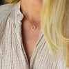 Woman wearing a Rosecliff small circle necklace featuring twelve 2 mm faceted round cut white topaz prong set in 14k gold