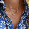 Woman wearing layered necklaces including a gold Rosecliff small open circle necklace with twelve 2 mm round cut white topaz