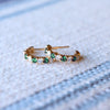 Pair of Rosecliff huggie earrings in 14k gold each featuring nine alternating 2 mm round cut emeralds and diamonds