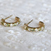 Pair of Rosecliff huggie earrings in 14k gold each featuring nine alternating 2 mm round cut peridots and diamonds