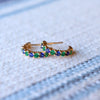 Pair of Rosecliff huggie earrings in 14k gold each featuring nine alternating 2 mm round cut sapphires and emeralds