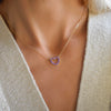 Woman wearing a Rosecliff Heart Necklace featuring twelve faceted round cut amethysts prong set in 14k yellow Gold