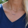 Woman wearing multiple necklaces including a 14k gold Rosecliff bar necklace with alternating diamonds, rubies & sapphires