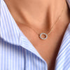 Woman with a Rosecliff small circle necklace featuring twelve 2mm faceted round cut aquamarines prong set in 14k yellow gold