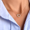 Woman wearing a Rosecliff small open circle necklace featuring twelve 2 mm round cut white topaz prong set in 14k gold