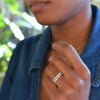 Woman with two Rosecliff stackable rings each featuring eleven 2 mm faceted round cut white topaz prong set in 14k gold