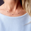 Woman wearing a Bayberry 11 Birthstone necklace featuring 4 mm briolette garnets bezel set in sterling silver