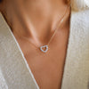 Woman wearing a Rosecliff Heart Necklace featuring twelve faceted round cut aquamrines prong set in 14k yellow Gold