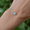 Woman with a Grand & Classic bracelet featuring one 6 mm Turquoise and four 4 mm Nantucket Blue Topaz bezel set in 14k gold