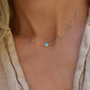Woman with a Grand & Classic necklace featuring one 6 mm Turquoise and four 4 mm Nantucket Blue Topaz bezel set in 14k gold