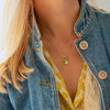 Woman wearing an Adelaide paper clip chain with a Warren emerald cut bezel set lemon verbena quartz pendant in 14k gold