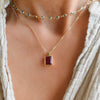 Woman wearing an Adelaide paper clip chain with a Warren emerald cut ruby pendant and a Newport necklace in 14k yellow gold