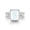 Warren ring in 14k white gold with accent diamonds featuring one 10 x 8 mm emerald cut rainbow moonstone - front view