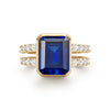 Warren ring in 14k yellow gold with accent diamonds featuring one 10 x 8 mm emerald cut bezel set sapphire - front view