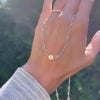 Woman holding a 14k gold Newport necklace featuring 4 mm gemstones and a 1/4” flat disc engraved with the letter H