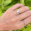 Hand wearing multiple rings including a 1.6 mm wide 14k gold Grand ring featuring one 6 mm bezel set moonstone