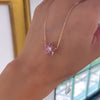 Woman holding a Greenwich necklace featuring five 4 mm pink tourmalines and one 2.1 mm diamond bezel set in 14k yellow gold