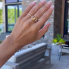 Braceleted woman's hand wearing a Rosecliff ring and a Warren ring in 14k gold with accent diamonds featuring one citrine