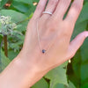 Woman holding a Grand 14k yellow gold 1.17 mm cable chain necklace featuring one 6 mm briolette cut bezel set sapphire