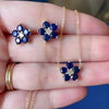 Woman holding a necklace and a pair of 14k gold Greenwich earrings each featuring five 4 mm sapphires & one 2.1 mm diamond