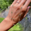 Woman holding a Bayberry Birthstone Wrap necklace featuring 4 mm briolette cut emeralds bezel set in 14k yellow gold