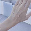 A woman's hand holding a Providence 5 White Topaz drop necklace featuring 5 petite baguette cut stones set in 14k gold