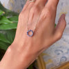 Hand with a Rosecliff small open circle necklace featuring twelve 2 mm faceted round cut sapphires prong set in 14k gold
