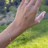 Woman holding a Greenwich cable chain necklace featuring one 4 mm sapphire and one 2.1 mm diamond bezel set in 14k gold