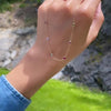 Woman holding a Personalized cable chain necklace featuring six 4 mm briolette cut gemstones bezel set in 14k yellow gold