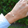 Woman wearing a 14k yellow gold Classic bracelet featuring birthstones and 1/4” flat letter-engraved discs