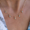 Woman wearing a Providence 5 Nantucket Blue Topaz drop necklace with petite baguette cut stones set in 14k yellow gold