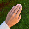 Hand wearing a Rosecliff stackable ring featuring eleven alternating 2 mm alexandrites and diamonds prong set in 14k gold