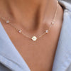 Woman with a 14k yellow gold Classic necklace featuring four moonstones and one 1/4” flat disc engraved with the letter H