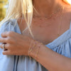 Woman wearing jewelry including a Sunset bracelet featuring alternating Pink Tourmalines and Citrines bezel set in 14k gold