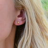 Close-up of a woman's ear wearing a Providence Citrine stud earring with a petite baguette stone set in 14k yellow gold
