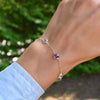 Woman wearing a Grand 1.17 mm cable chain bracelet in 14k gold featuring four 6 mm briolette cut bezel set gemstones