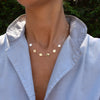 Woman with a 14k yellow gold cable chain necklace featuring six 1/4” flat discs engraved with letters