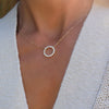 Woman with a Rosecliff open circle necklace with sixteen 2 mm faceted round cut white topaz prong set in 14k yellow gold