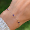 Woman with a Bayberry 1.17 mm cable chain bracelet featuring three 4 mm briolette cut amethysts bezel set in 14k gold