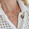 Woman wearing a Providence 5 Emerald drop necklace with petite baguette cut stones set in 14k yellow gold