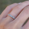 Hand with a Rosecliff stackable ring featuring eleven 2 mm faceted round cut Nantucket blue topaz prong set in 14k gold