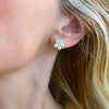 Woman wearing a 14k yellow gold Greenwich 5 Birthstone earring featuring five 4 mm round cut opals and one 2.1 mm diamond