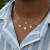 Woman wearing a Joy Over Everything 14k yellow gold Necklace featuring two 4 mm Moonstones and three 1/4