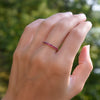 Hand with a Rosecliff stackable ring featuring eleven 2 mm faceted round cut rubies prong set in 14k yellow gold